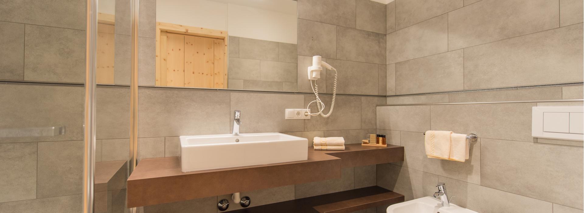 Badezimmer des Doppelzimmers Sepp Innerkofler Süd mit Dusche, Waschtisch, Bidet und WC