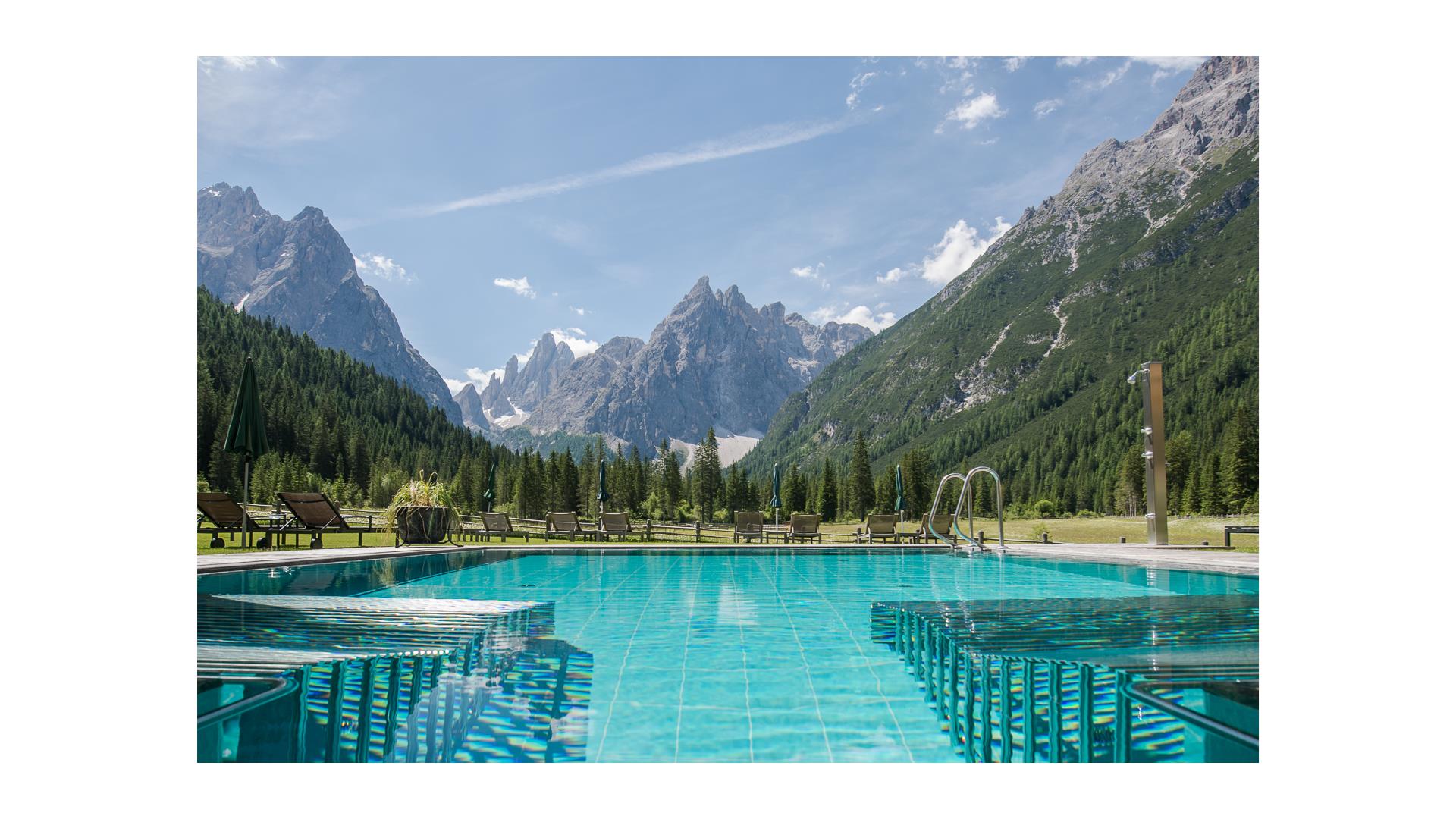 The outdoor pool with whirlpool benches and a view on the Dolomites